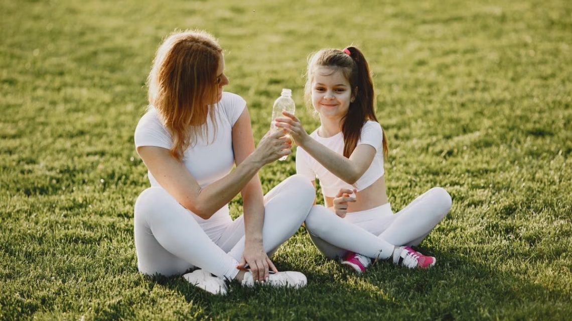 Caucasian mother and daughter in sportswear sharing a bonding moment outdoors.